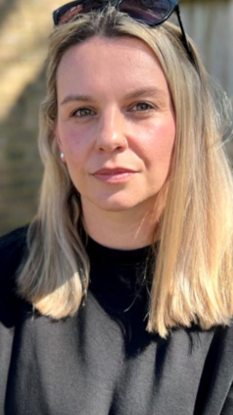 Rachel Moore looks at the camera. She has shoulder length blonde hair with a pair of black sunglasses on top of her head and wears a black cotton t shirt.