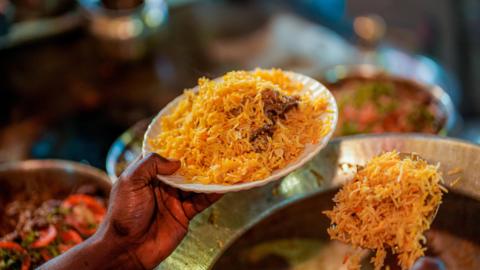 A man serving a plate of biryani in Lucknow