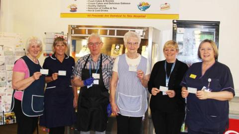The Volunteers’ Coffee Lounge team with neonatal matron Vicky Ford and nurse consultant Lynne Paterson. They are standing in a row holding meal vouchers.