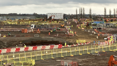A large building site with workers scattered around.