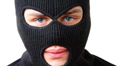 A man wearing a black balaclava. Only his lips and eyes are visible.