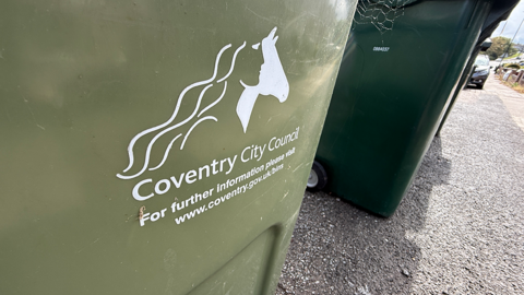 A close-up of two green garden waste bins