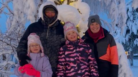 Laura her husband and daughters pose in front of a snow covered tree in Lapland