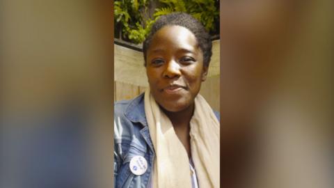 Kimberley Wilson wears a blue denim jacket and a cream scarf. She's wearing a badge that reads "Baby on board".
