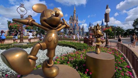  Statues of Mickey Mouse and Minnie Mouse stand in a garden in front of Cinderella's Castle at the Magic Kingdom Park at Walt Disney World on April 3, 2025, in Orlando, Florida.