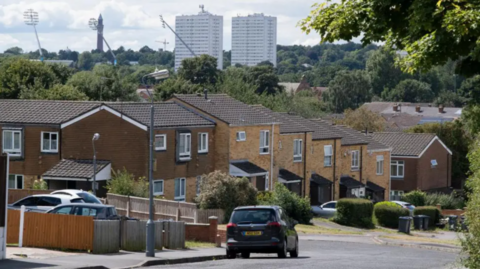 A picture of a black car driving on a residential street in Birmingham.