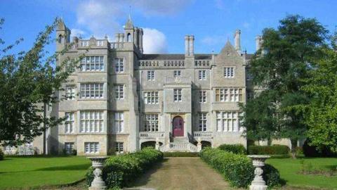 The outside of Abbey College in Ramsey. It is a grand building with a shrub-lined drive leading up to it.