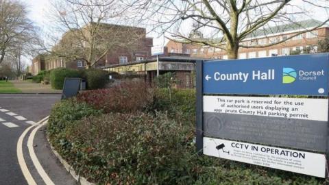 A sign reading 'County Hall' with a brick building in the background