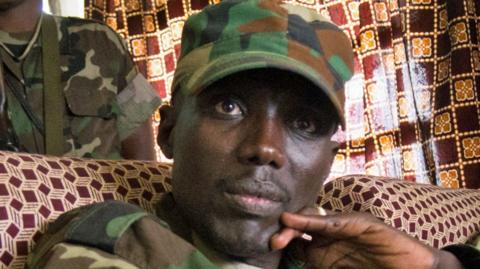 Sultani Makenga, wearing a military cap, looks into the camera