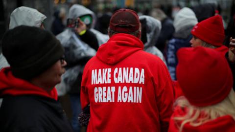 A Donald Trump supporter wears clothing with "Make Canada Great Again" written on the back.