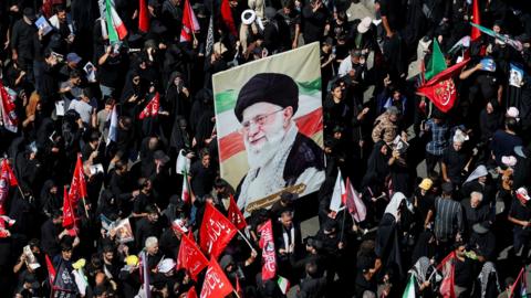 crowds holding poster showing former supreme leader