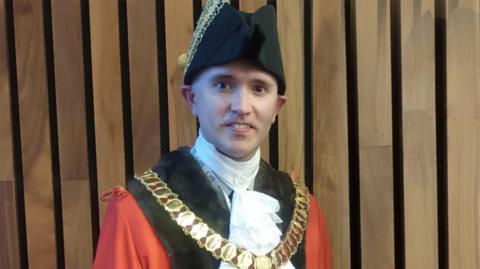 Ross Armour wearing a black bicorne hat and a red and black robe with a mayor's chain of office