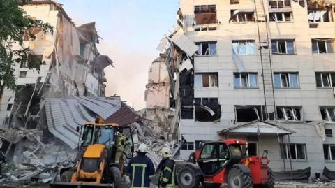 Rescuers and an excavator at the scene near a destroyed dormitory building of the Starobilsk College. 