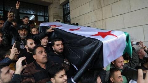 A flag-draped casket is carried during a funeral for Syrian activist Mazen al-Hamada on December 12, 2024 in Damascus, Syria