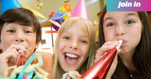 Three kids blowing noise makers at birthday party.