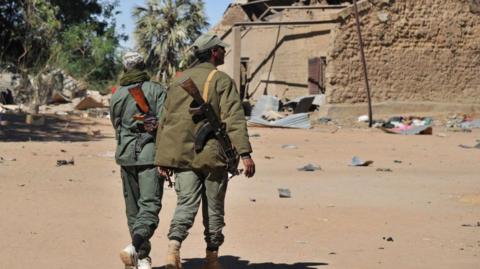 Malian soldiers inspect army buildings in Diabaly that had been seized by Islamic jihadists and later destroyed in air strikes as they arrive in the city