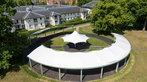 An aerial view of a large white circular canopy in a park
