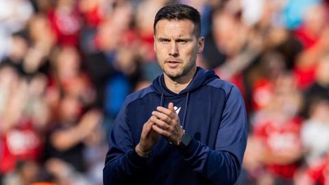 Walsall FC manager Matt Sadler wearing tracksuit applaudes players and fans after their latest win