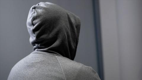 Anonymous fan in a hoody from behind