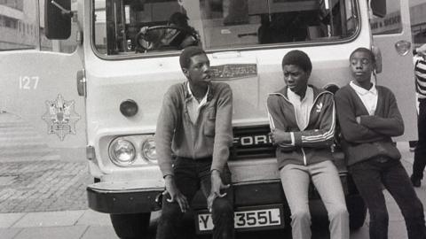 Three boys lean on a fire engine in Coventry city centre