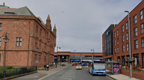 A Google Streetview image of Market Street in Barrow, with the Holiday Inn on the right and historic buildings on the left.