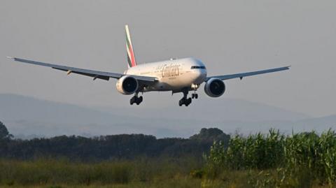 A Emirates 777 low flying over a green expanse just outside of Leonardo Da Vinci airport in Fiumicino