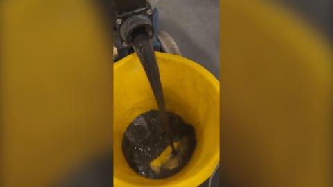 Black liquid pours from with fluid collected from Tube seats into bucket