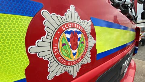 The side of a red fire engine with the Scottish Fire and Rescue Service badge.