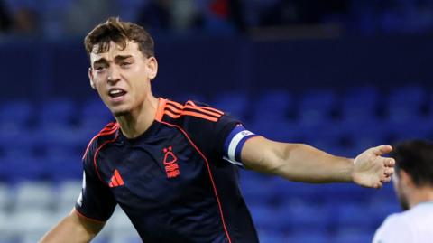 Jack Thompson with his arms outstretched appealing for a decision towards an official (out of the picture), wearing Nottingham Forest's navy away kit 