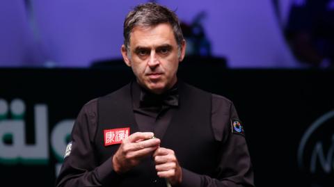 Ronnie O'Sullivan chalking his cue