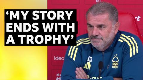 Nottingham Forest head coach Ange Postecoglou wearing a Nottingham Forest tracksuit, with a red background.