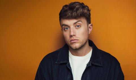 Roman Kemp poses in front of an orange background for his new BBC Three documentary.