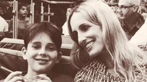 A black and white photo of a woman smiling at her child.