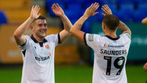 Midfielder Josh Williams smiles broadly and high-fives a Tranmere Rovers team-mate