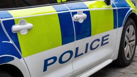 Close up of a United Kingdom police patrol response car with Battenberg markings.