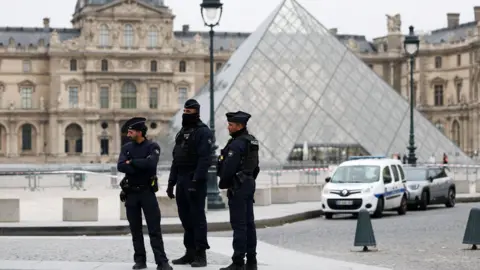 Security personnel standing near a glass pyramid building