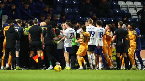 There is a coming together involving players of both Preston and Hull City with stewards in lime green bibs and some with fluorescent jackets trying to separate members of both sides' backroom teams 
