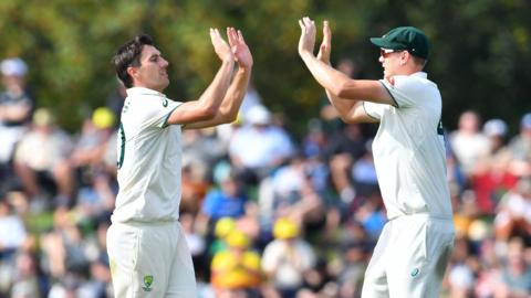 Australia's Pat Cummins (L) celebrates the wicket of New Zealand's Tim Southee with his teammate Cameron Green
