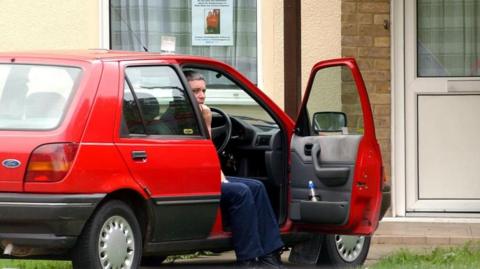 Ian Huntley sitting in his car outside his house in Soham, Cambridgeshire in August 2002