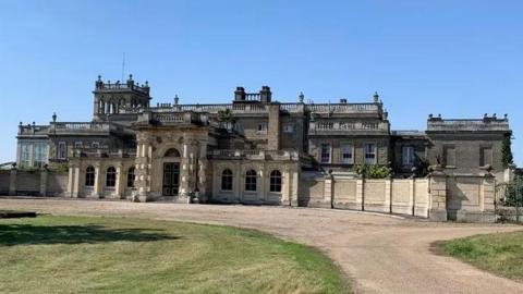 Shrubland Hall is a large historic building which has a large driveway in front of it. The building has a main entrance in the middle.