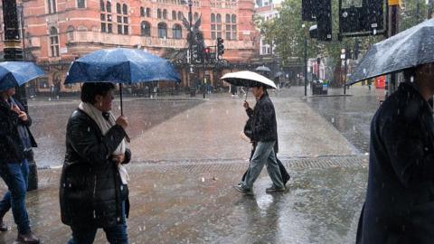Image of people walking in a street with umbrellas protecting them from the heavy rainfall
