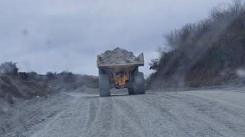 A large truck driving through a clay pit carrying heavy material