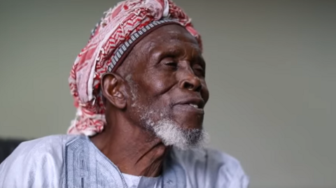 A head and shoulders image of Imam Abubakar Abdullahi looking to the side during an interview.