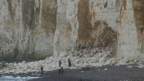 People gathered by the bottom of a cliff