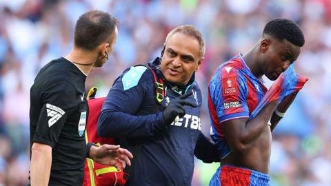 Marc Guehi leaves the pitch after being treated for an injury