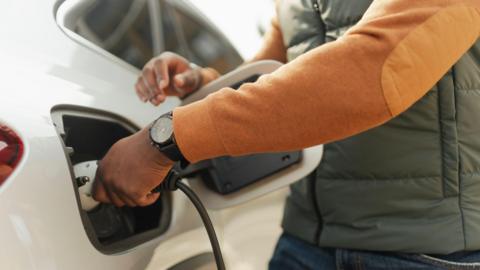 Person plugging in charger for white electric car