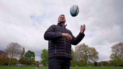 Dan Biggar in a field playing with a rugby ball