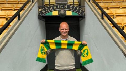 New Norwich City head coach Liam Manning holding a club scarf at the entrance of the players' tunnel