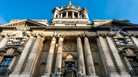 The exterior of the Old Bailey in London. The court building has several stone columns and ornate details. 