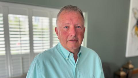 Deputy Liam McKenna - A man with grey hair and a red face looking at the camera. He is wearing a turquoise shirt.